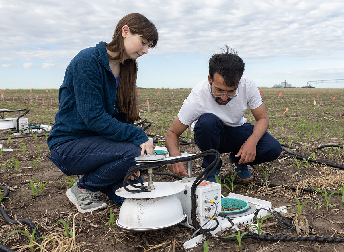 Skye Brugler and Shailesh Pandit work in the field with greenhouse gas emission chambers
