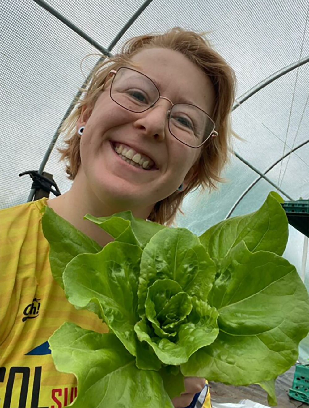 Ph.D. researcher Katie Allen alongside a lettuce that was grown in human poop compost. Photo by Katie Allen.