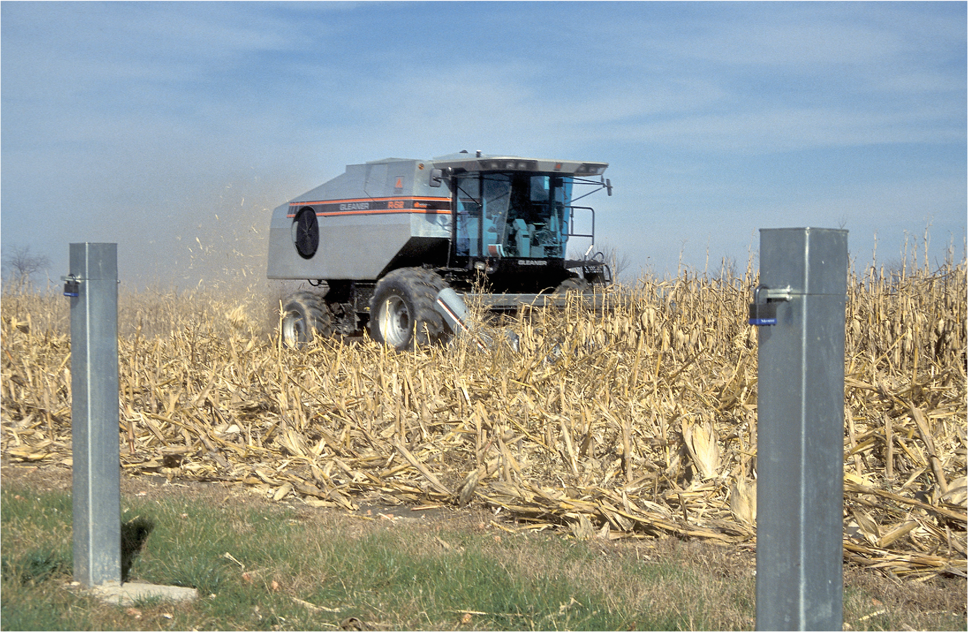 A combine passes through the field with groundwater wells in the foreground. USDA-ARS photo by Newell Kitchen.