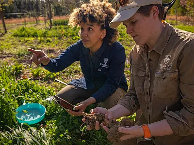 Dianna Bagnall (right) examines soil during a field visit with a colleague. The Soil Health Institute aims to make sustainable ag practices profitable for U.S. farmers. Their work wouldn’t be possible without federal funding. Photo courtesy of Dianna Bagnall.