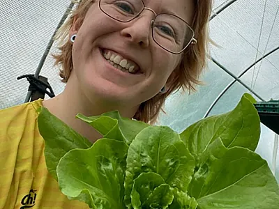 Ph.D. researcher Katie Allen alongside a lettuce that was grown in human poop compost. Photo by Katie Allen.