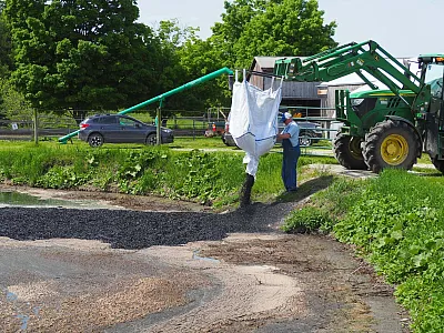 Sam Dixon, dairy farm manager at Shelburne Farms in Shelburne, VT, applies biochar to an earthen manure pit. Photo courtesy of Shelburne Farms.