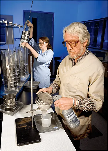 Researchers prepare to separate soil aggregates and wash a sep- arated aggregate sample off of a soil sieve into a container to  determine the amount and origin of the carbon sequestered in the sample. Photo by Stephen Ausmus, USDA-ARS.
